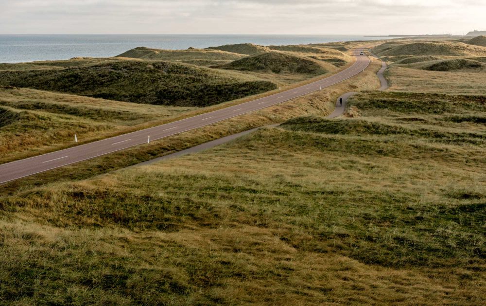 Vej i klitlandskab med hav i det fjerne