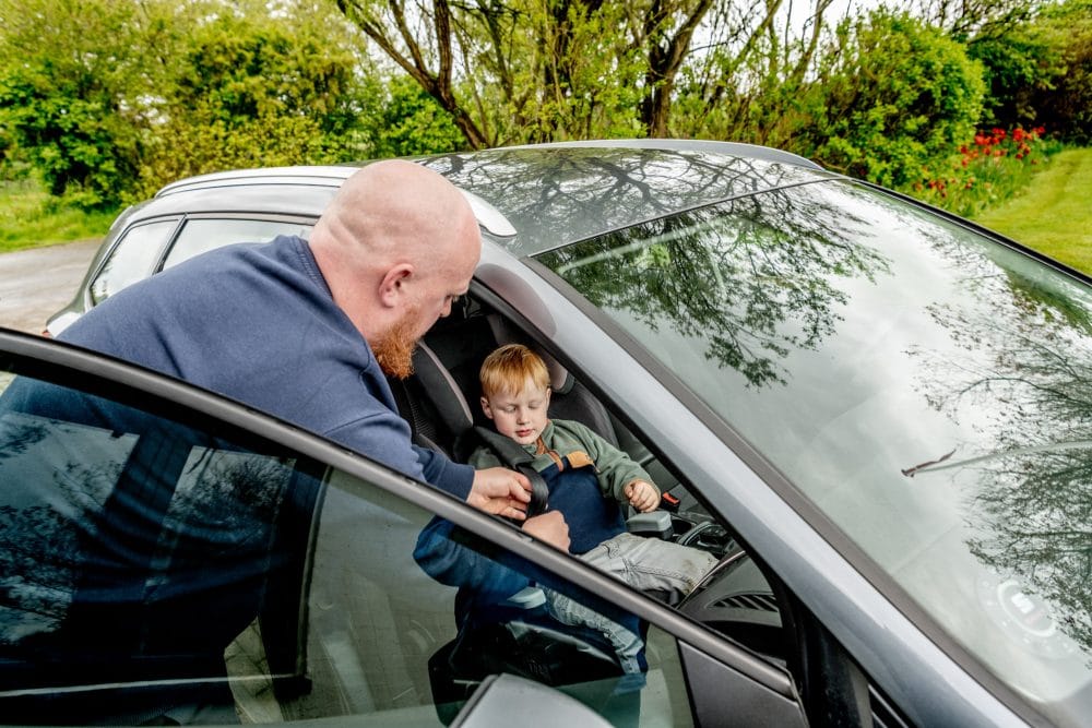 en mand spænder bilsele på en dreng