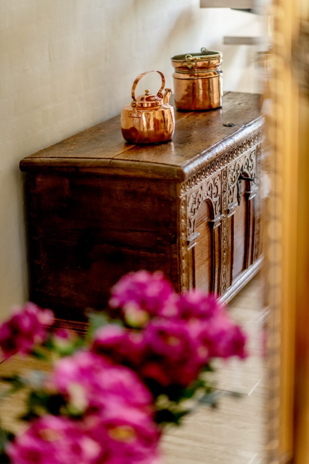 en trækasse står på et gulv ved en pink plante