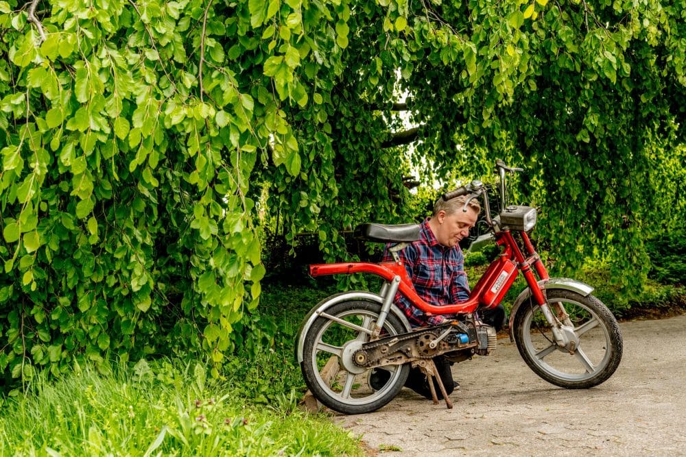 en mand står ved en gammel knallert