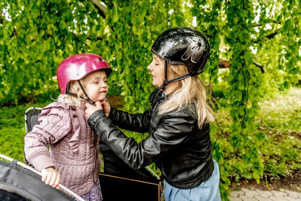 en kvinde putter en hjelm på pige