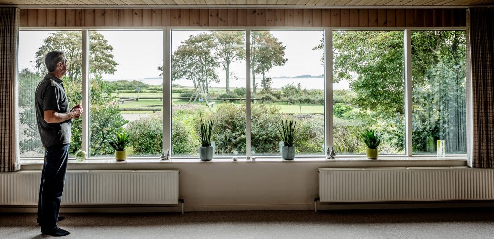 Mand kigger ud af stuevindue