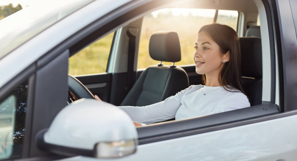 Ung kvinde kører bil. Køb bilforsikring til unge